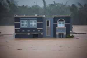 Three people inside a house await rescue from the floods caused by Hurricane Fiona in Cayey, Puerto Rico, Sunday, September 18, 2022. (AP Photo/Stephanie Rojas)