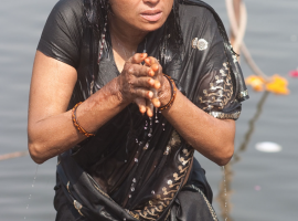 A woman offering up prayers as part of her morning puja on the bathing ghat in Ujjain, Madhya Pradesh.