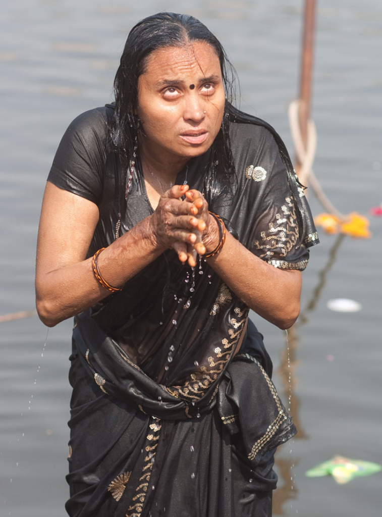 A woman offering up prayers as part of her morning puja on the bathing ghat in Ujjain, Madhya Pradesh.